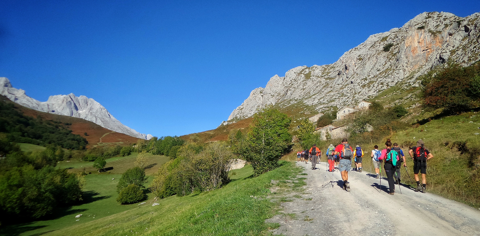 hikers-walking-through-pathway-surrounded-by-hills-covered-in-greenery-under-the-sunlight (1)